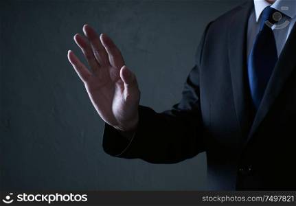 Closeup businessman in suit touch gesture pose isolated on dark background .