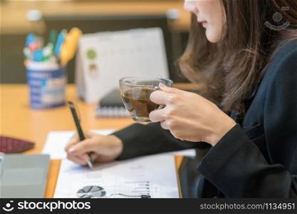 Closeup businesswoman hand drinking coffee when working with with computer laptop and office supplies in modern office or meeting room, Business and worker concept