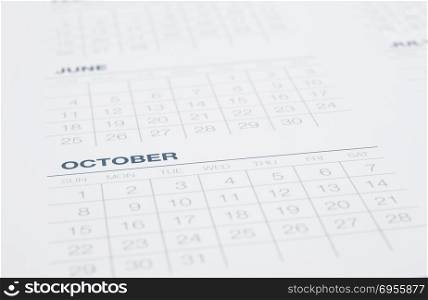 Closeup calendar page focus on October, blurred the months pass, weekly start on sunday. Clean blue tone background with modern minimal style. Business vision, mission, timetable, year end review.