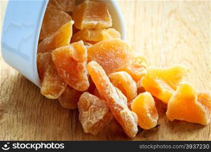 Closeup candied crystallized ginger candy pieces in white bowl. Healthy eating, home remedy for nausea inflammation, colds.
