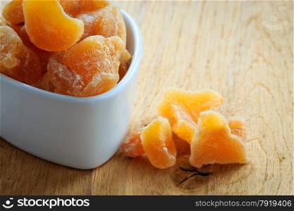 Closeup candied crystallized ginger candy pieces in white bowl. Healthy eating, home remedy for nausea inflammation, colds.