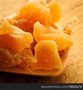 Closeup candied crystallized ginger candy pieces on wooden spoon. Healthy food, home remedy for nausea motion sickness, colds.