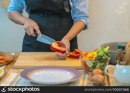 Closeup chef hand cutting the bell pepper on the Chopping board in modern kitchen, diet and healthy food concept