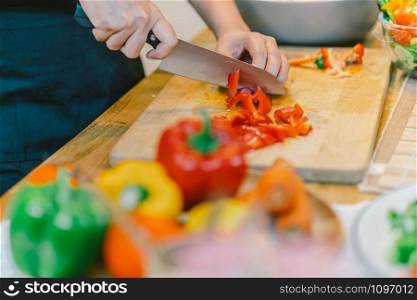 Closeup chef hand cutting the bell pepper on the Chopping board in modern kitchen, diet and healthy food concept