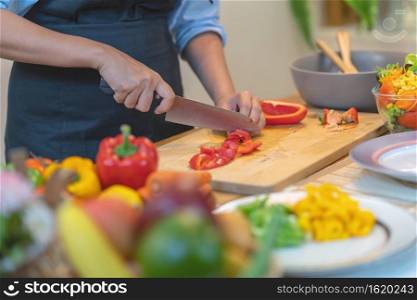 Closeup chef hand cutting the bell pepper on the Chopping board in modern kitchen, diet and healthy food concept