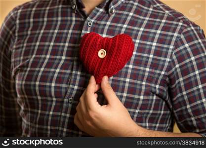 Closeup conceptual photo of man holding red heart on chest