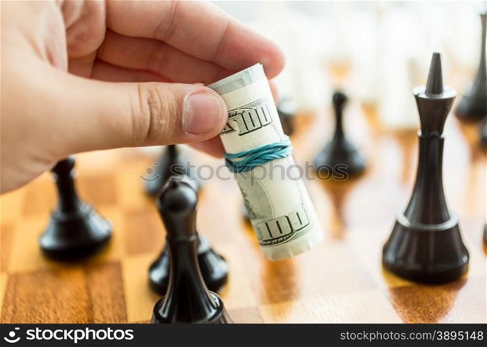 Closeup conceptual photo of man making move at chess game with dollar bills