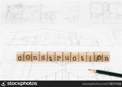 closeup construction word block stack on blueprints and floor plan, architecture concept