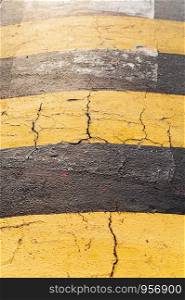 Closeup cracked yellow stripes concrete speed bump with yellow sunlight. Drive safety concept wallpaper.