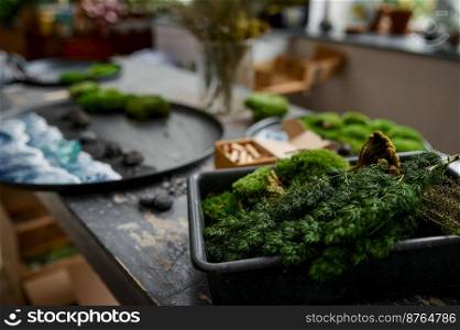 Closeup creative art workspace selective focus. Hand craft design elements on table. Moss, stones, flower and herbs for decorative platter creation. Closeup creative art workspace selective focus