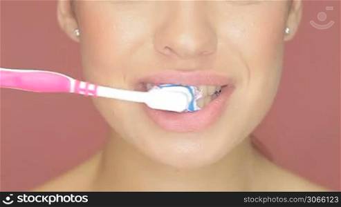 Closeup cropped view of the mouth of a smiling woman with a toothbrush and toothpaste