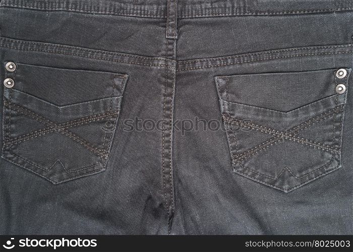 Closeup detail of black denim jeans trousers pocket, texture background. Top view with copy space