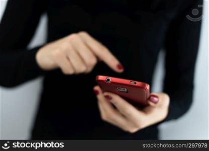 Closeup detail of young woman holding a red cell phone with camera using a touchscreen with apps to connect on social media, texting, chatting and messaging.. Closeup detail of young woman holding a red cell phone with camera using a touchscreen with apps to connect on social media, texting, chatting and messaging