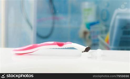 Closeup disposable pink razor blade laying in in bathroom on white sink
