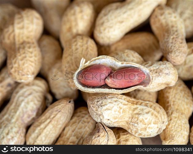 Closeup dried peanuts in shells on peanuts background on wooden table. Concept of snack