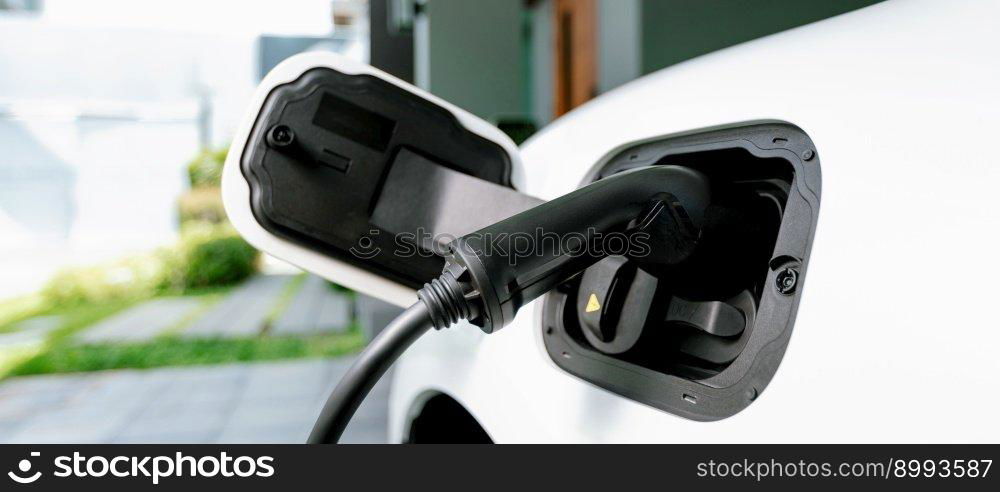 Closeup e≤ctric vehic≤plug≥d-in with cab≤from charging po∫powered for progressive concept by a<ernative c≤an e≠rgy rechar≥ab≤EV car at home charging station.. EV car plug≥d-in with cab≤from progressive home charging station.