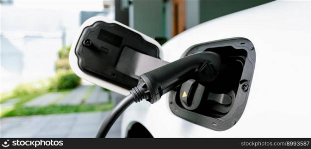 Closeup e≤ctric vehic≤plug≥d-in with cab≤from charging po∫powered for progressive concept by a<ernative c≤an e≠rgy rechar≥ab≤EV car at home charging station.. EV car plug≥d-in with cab≤from progressive home charging station.