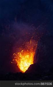 Closeup explosion in volcano spits lava and fire in darkness