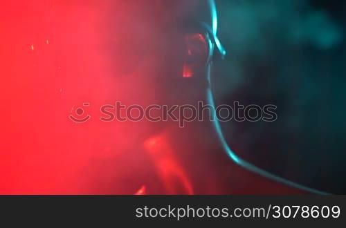 Closeup face of female mannequin in blue glowing led glasses over dark smokey background