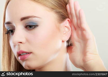 Closeup female hand to ear listening on gray. Gossip girl with palm behind ear spying. Young woman listening secret.