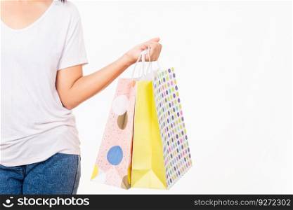 Closeup female holds in hand with multicolor clear empty blank craft paper gift bag, women hand holding colorful shopping bag many packets isolated on white background, shopping day concept