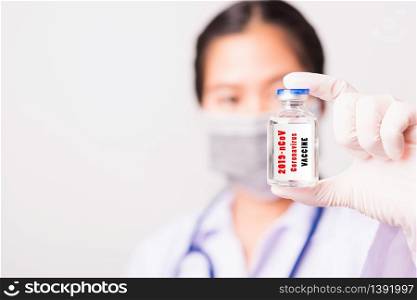 "Closeup female woman doctor or scientist in uniform wearing face mask protective in lab use hand finger hold vial vaccine bottle, and on vial vaccine have "CORONAVIRUS VACCINE" text label, COVID-19"