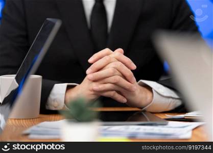 Closeup focus boss body language executive, CEO sitting confidently at meeting table or desk in professional harmony office workplace with hand clasped together, thinking and making business decision.. Closeup focus boss sitting at the meeting table as harmony concept in workplace.