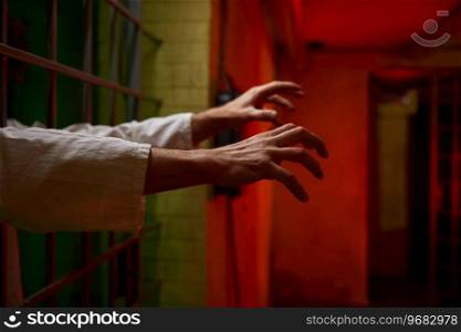 Closeup focus on creepy reaching hands with curled fingers of psychiatric clinic patient from cage ward. Closeup focus on reaching hands of psychiatric clinic patient
