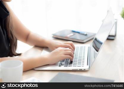Closeup freelance asian woman working and typing on laptop computer at desk office with professional, girl using notebook checking email or social network, business and lifestyle concept.