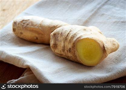 Closeup fresh raw ginger rhizome root on rustic table. Healthy eating, home remedy for nausea inflammation, colds.