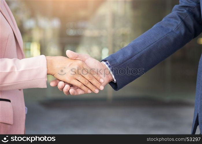 Closeup friendly meeting handshake between business woman and businessman with sunlight.