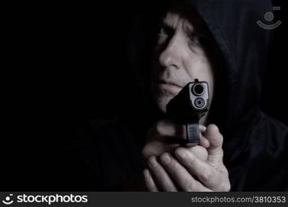 Closeup front view of pistol in front of desperate man in dark background