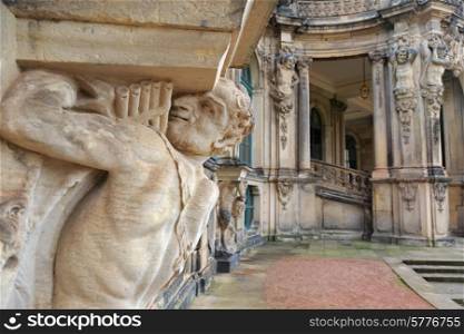 Closeup half naked faunus statue under column with panpipe at Zwinger palace in Dresden, Germany&#xA;