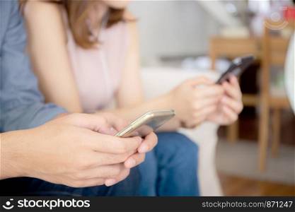 Closeup hand asian couple sitting on sofa with problem about relationship because addicts social network media together, asia family expression with looking phone with ignoring and indifferent.