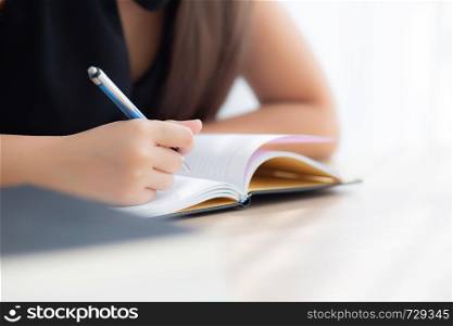 Closeup hand asian woman sitting study and learning writing notebook and diary on table in living room at home, girl homework, business writer woman working on table, education concept.
