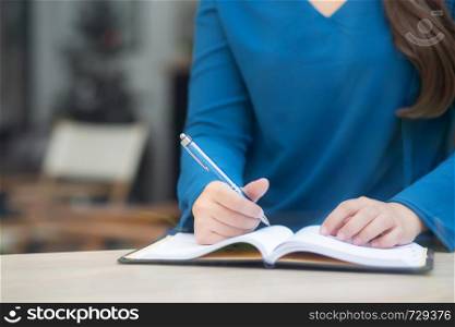 Closeup hand asian woman sitting study and learning writing notebook and diary on table in at cafe shop, girl homework, business writer female working on table, education concept.