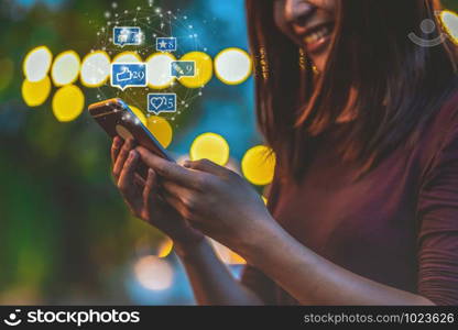 Closeup hand of Asian woman using smartphone and touching screen for social netwrok media with number of Like, Love, comment, people and fovorite icon at outdoor park, Business and Lifestyle concept