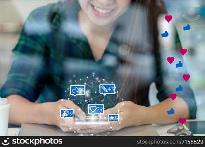 Closeup hand of Asian woman using smartphone and touching screen for social netwrok media with number of Like, Love, comment, people and fovorite icon at desk beside glass, Social network concept