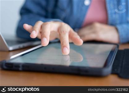 Closeup hand of asian women are using tablet on wood table