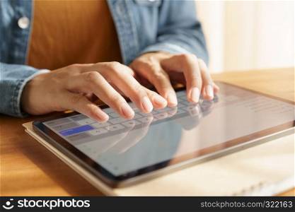 Closeup hand of asian women are using tablet on wood table