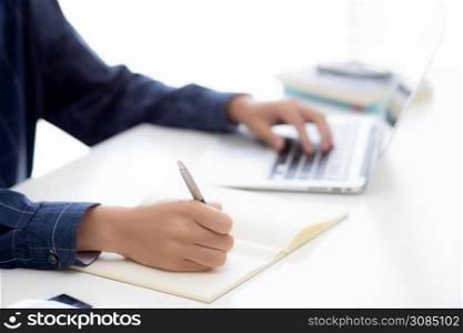Closeup hand of business man writing on note while using laptop computer on desk at home, male planning on note for business success, author and blog, businessman working on table, employee and job.