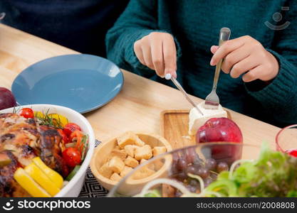 Closeup hand of children eating food at home on Christmas day, thanksgiving eve, family with kid sitting cozy on food table for relax while decoration in celebration xmas and holiday.