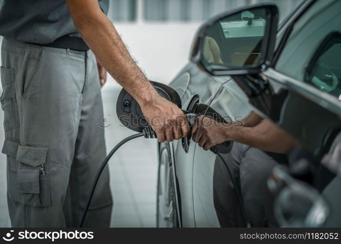 Closeup hand of technicial charging the car electrict in maintainance service center which is a part of showroom, economic and technology for safe the world concept