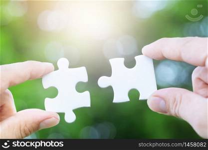 Closeup hand of woman connecting jigsaw puzzle with sunlight effect, Business solutions, success and strategy