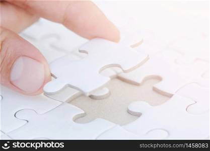 Closeup hand of woman connecting jigsaw puzzle with sunlight effect, Business solutions, success and strategy