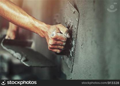 closeup hand of worker plastering cement at wall for building house