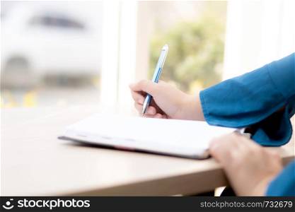 Closeup hand woman writer thinking idea and writing on notebook or diary with happy, lifestyle of asian girl is student, female planning working, education and business concept.