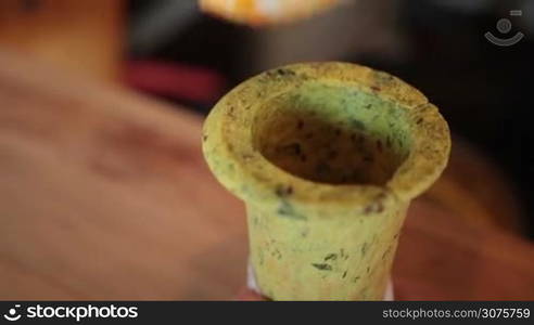 Closeup hands filling with spoon edible baked cone with hot vegetable soup and serving with mint leaf