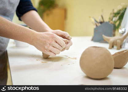 Closeup hands of ceramic artist wedging clay on a desk in art studio.. Closeup hands of ceramic artist wedging clay on a desk in art studio