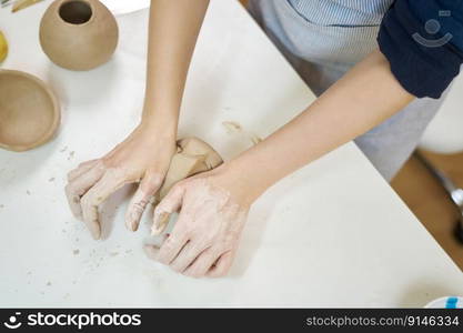 Closeup hands of ceramic artist wedging clay on a desk in art studio.. Closeup hands of ceramic artist wedging clay on a desk in art studio